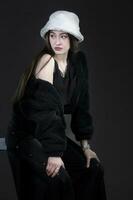 Beautiful stylish girl in a fur hat on a dark background. photo