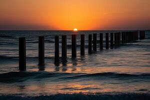 Beautiful sunset over the Baltic Sea with wooden breakwaters in the foreground photo