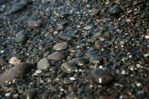 Wet small stones in seawater close-up. Pebble beach photo