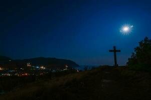 noche paisaje. el cruzar de Dios en un colina con vista a el afueras de el ciudad y el mar. un pequeño pueblo en el Crimea. marina. foto