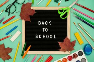 Text Back to school soon on a wooden letter board. buying stationery, flat, bright background. Maple leaves. Autumn school fees. photo