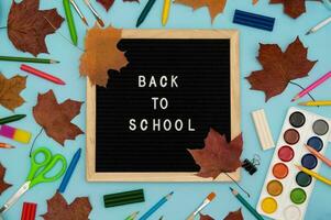 Text Back to school soon on a wooden letter board. buying stationery, flatlay, bright background. Maple leaves. Autumn school fees. photo