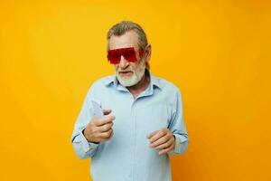 Portrait elderly man in fashionable red glasses with a phone isolated background photo