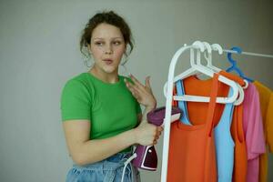 pretty woman ironing clothes on a hanger wardrobe light background unaltered photo