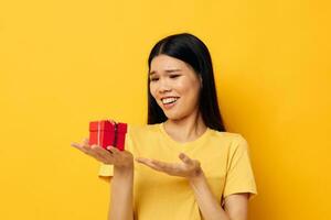 Charming young Asian woman Little red gift box fun yellow background unaltered photo