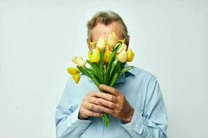 antiguo hombre en un azul camisa con un ramo de flores de flores ligero antecedentes foto