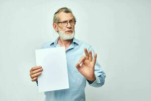 Portrait of happy senior man in a blue shirt and glasses a white sheet of paper cropped view photo