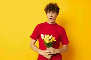 Young curly-haired man in a red t-shirt a bouquet of flowers holiday gift Lifestyle unaltered photo