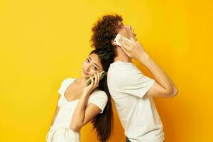 young couple talking on the phone yellow technology background photo