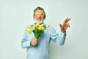 Photo of retired old man a bouquet of flowers with glasses as a gift light background