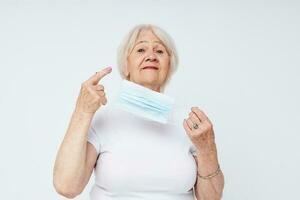 Photo of retired old lady medical mask in hand safety light background