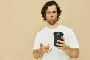 hermoso hombre en un blanco camiseta con un negro vaso en mano estilo de vida inalterado foto