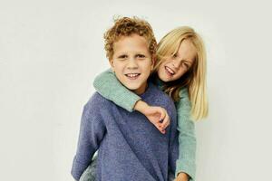 Boy and girl in multi-colored sweaters posing for fun light background photo