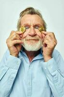 Portrait of happy senior man in a blue shirt bitcoins on the face cropped view photo