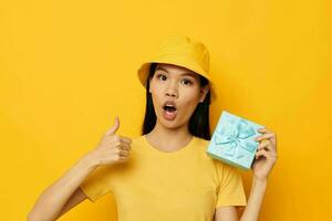 pretty brunette in a yellow T-shirt and a hat with a gift studio model unaltered photo