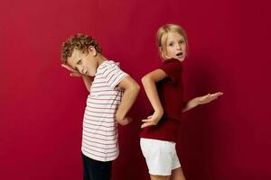 Cute preschool kids emotions stand side by side in everyday clothes red background photo