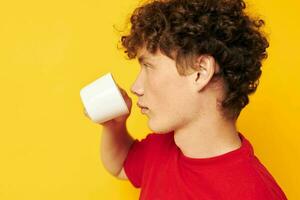 cute red-haired guy posing with a white mug and in the hands of a drink yellow background unaltered photo