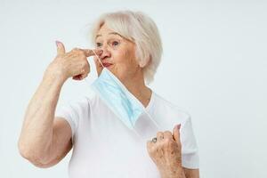 elderly woman in casual t-shirt and medical mask light background photo