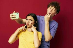 nice guy and girl in colorful T-shirts with a phone red background photo