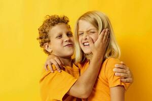 pequeño niños en amarillo camisetas en pie lado por lado infancia emociones amarillo antecedentes foto