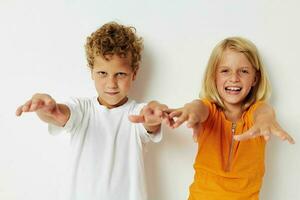 two joyful children posing hand gesture smile casual wear light background photo