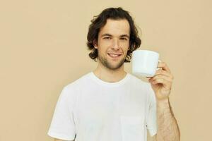 Attractive man with a white mug in his hands emotions posing beige background photo