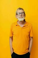 Portrait of happy senior man with a gray beard in glasses yellow background photo