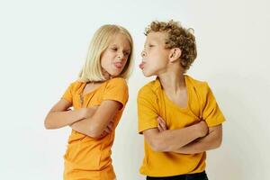 Cute stylish kids in yellow t-shirts standing side by side childhood emotions light background unaltered photo