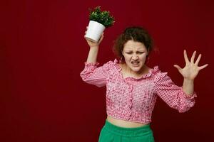 emotional girl with flower pot posing red background photo