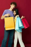 young boy and girl colorful bags shopping fun red background unaltered photo