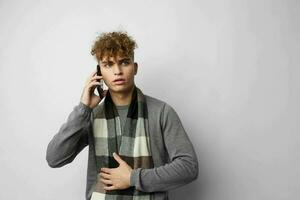 Attractive man in a plaid scarf talking on the phone posing emotions isolated background photo