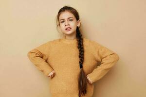 Portrait of happy smiling child girl long pigtail beige sweater grimace beige background photo