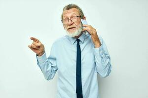 Photo of retired old man in a shirt with a tie with a phone technology light background