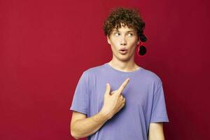 Young curly-haired man hand gestures heart shaped glasses posing isolated background photo