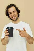 Cheerful man in a white T-shirt with a black glass in hand beige background photo