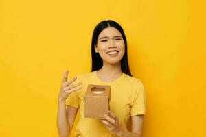 woman holding a small box gift yellow background photo