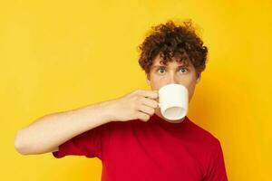 cute red-haired guy posing with a white mug and in the hands of a drink yellow background unaltered photo