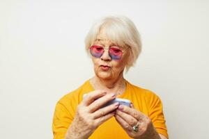 smiling elderly woman in fashionable glasses with a smartphone in hand cropped view photo