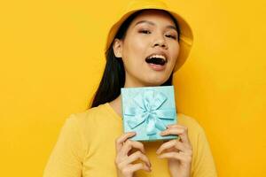 Portrait Asian beautiful young woman with a gift box in his hands surprise emotions yellow background unaltered photo