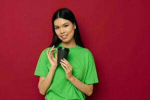 retrato asiático hermosa joven mujer sonrisa verde camiseta negro desechable tazas Moda rojo antecedentes inalterado foto