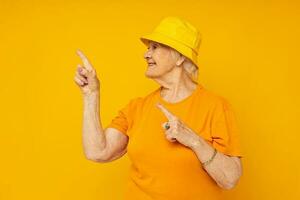 Portrait of an old friendly woman in casual t-shirt yellow panama yellow background photo