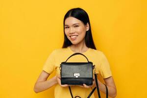 Portrait Asian beautiful young woman female clutch accessories posing yellow background unaltered photo