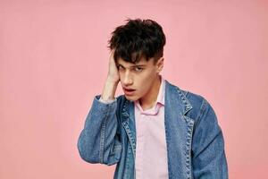 retrato de un joven hombre en juventud elegante ropa mezclilla chaqueta posando rosado antecedentes inalterado foto