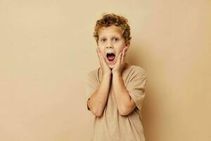 boy in a beige t-shirt with curly hair posing photo