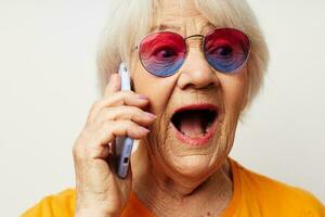 Photo of retired old lady in fashionable glasses with a smartphone in hand close-up emotions