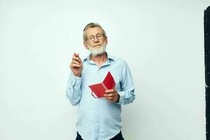 Portrait of happy senior man with red notebook and pen light background photo