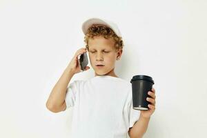 linda pequeño chico hablando en el teléfono con un negro vaso ligero antecedentes inalterado foto
