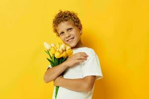 Photo portrait curly little boy holding a bouquet of flowers a gift yellow background unaltered