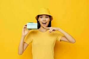 bonito morena en un amarillo camiseta y un sombrero con un regalo estudio modelo inalterado foto