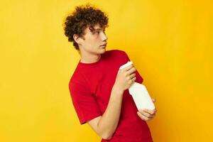 portrait of a young curly man in a red t-shirt detergents in hands posing Lifestyle unaltered photo